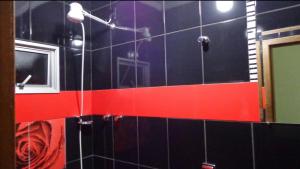 y baño con ducha y azulejos rojos y negros. en Hotel Real de Caeté, en Caeté