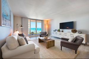 1 Hotel & Homes Miami Beach Oceanfront Residence Suites By Joe Semary في ميامي بيتش: غرفة معيشة مع أريكة بيضاء وتلفزيون