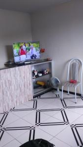 ein Wohnzimmer mit einem TV und einem Stuhl in der Unterkunft Bourguignon in Piúma