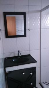 uma casa de banho com um lavatório preto e um espelho em Bourguignon em Piúma