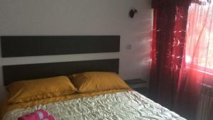 ブシュテニにあるBuşteni Houseのベッドルーム1室(ヘッドボードと赤いカーテン付きのベッド1台付)