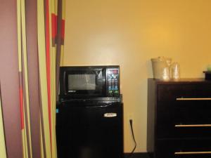 a microwave sitting on top of a black refrigerator at Dynasty Hotel and Suites New York LaGuardia Hotel in Queens
