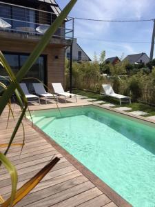 a swimming pool on a deck with chairs and a house at Villa Mané Lann Maison d'hôtes & spa in Carnac