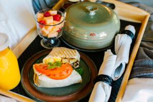 a sandwich on a plate on a tray with a bowl of fruit at Pine River Ranch B&B in Leavenworth