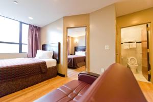 a hotel room with two beds and a couch at Dynasty Hotel and Suites New York LaGuardia Hotel in Queens