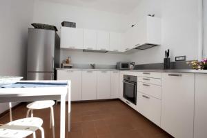 Casa Bianca - Goelba في بومونته: مطبخ مع دواليب بيضاء وطاولة مع كراسي