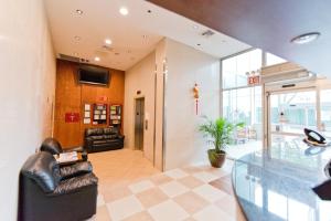 a lobby with leather chairs and a glass table at Dynasty Hotel and Suites New York LaGuardia Hotel in Queens