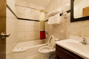 a bathroom with a toilet and a sink at Dynasty Hotel and Suites New York LaGuardia Hotel in Queens +39 photos