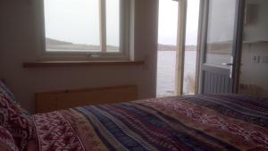 a bedroom with a bed and a window with the water at Otter Bothy in Uig