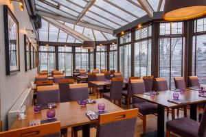 a restaurant with wooden tables and chairs and windows at Ferryhill House Hotel in Aberdeen