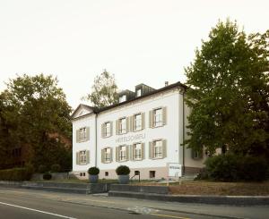 un bâtiment blanc sur le côté d'une rue dans l'établissement Hotel Schäfli, à Uzwil