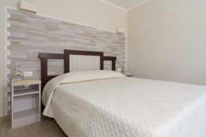 a bedroom with a white bed and a brick wall at La Cycas Accommodation in Tropea