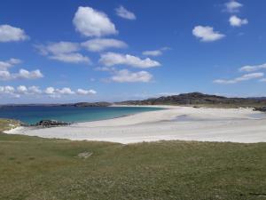 a beach with sand and water and mountains in the background at Otter Bothy in Uig