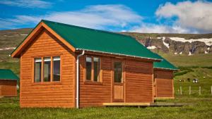 eine Holzhütte mit einem grünen Dach auf einem Feld in der Unterkunft Hvammstangi Cottages in Hvammstangi