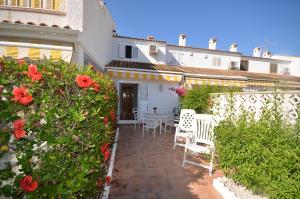 un patio con sillas blancas y flores rojas frente a una casa en APCOSTAS - Gran Vista, en Gran Alacant