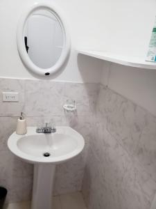 Baño blanco con lavabo y espejo en SANDY BOTTOM COTTAGES, en Mount Thompson
