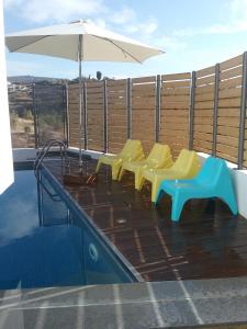 a group of yellow and blue chairs and an umbrella at Agnanti Apartments in Argaka