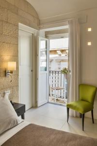 a bedroom with a bed and a green chair at Sciala Ortigia B&B in Siracusa