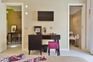 a bedroom with a desk and a pink chair at Sciala Ortigia B&B in Siracusa