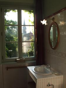baño con lavabo, espejo y ventana en Le Domaine De Pomone, en Woinville