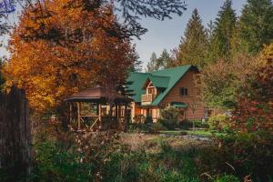 a large wooden house with a green roof at Cowichan River Lodge in Lake Cowichan