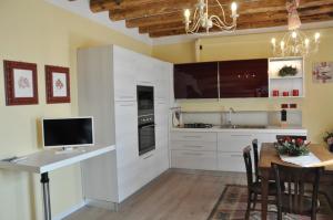a kitchen with white cabinets and a table with a television at Casa della Magnolia in Conegliano