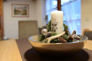 une bougie assise dans un bol avec des décorations de Noël dans l'établissement Miraval Perathoner Andreas, à Ortisei