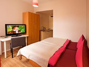 a bedroom with a bed and a desk with a television at Hotel PurPur in Prague