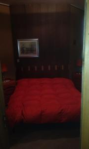 a red bed in a bedroom with a red comforter at bilocale Giomein in Breuil-Cervinia