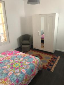 a bedroom with a bed and a chair and a mirror at JOLIE PETITE MAISON in Villepinte