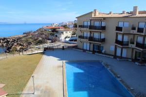 a building with a swimming pool next to the ocean at APARTAMENTO L'ESCALA in L'Escala