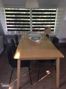 una mesa de madera con sillas en una habitación con ventanas en Bosvilla Ardennen, en Durbuy