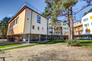 an apartment building with a tree in front of it at Apartamenty Poddąbek- basen kryty, sauna, animacje dla dzieci , małpi gaj, baseny na dachu in Poddąbie