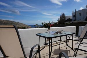 una mesa con un jarrón de flores en el balcón en Glafki Hotel Tinos, en Pánormos