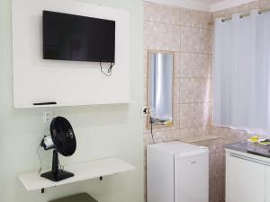 a white kitchen with a black fan on a wall at Hostel Trem de Minas in Belo Horizonte