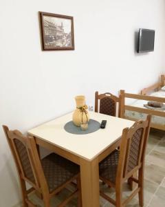 uma mesa com cadeiras e um vaso em cima em Apartmani Maja Zrenjanin em Zrenjanin