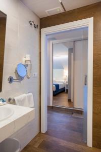 a bathroom with a sink and a mirror and a bed at Hotel Boutique Barra Alta (Adults Only) in Peñíscola