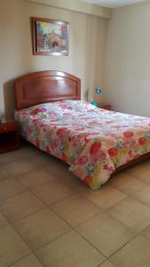 a bedroom with a bed with a floral comforter at Hostal La Casona in Pisco