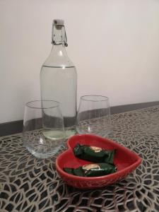 two wine glasses and a red bowl with a bottle at Sleep Well Apartment in Glasgow