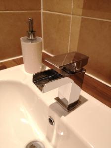 a bathroom sink with a chrome faucet on it at Sleep Well Apartment in Glasgow