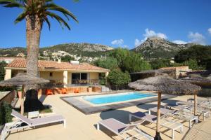 a villa with a swimming pool and a palm tree at Clos des Oliviers in Lumio