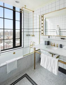 a bathroom with a tub and a sink and a mirror at The Ludlow Hotel in New York