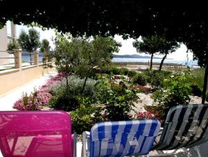 two chairs sitting next to a garden with flowers at Apartments Mira - 20 m from pebble beach in Zaboric