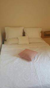 een wit bed met een roze kussen erop bij Zlatibor Apartman Pantic in Zlatibor