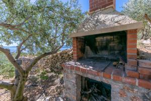 an outdoor brick oven with a tree in the background at House Petric in Bol +35 photos
