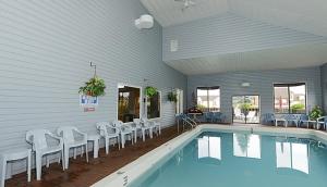 a swimming pool with white chairs next to a house at Americas Best Value Inn Saint Ignace in Saint Ignace