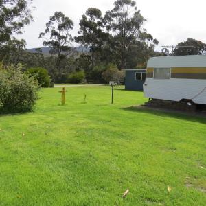 a white truck parked in a grassy area next to a fence at Captain Cook Holiday Park in Adventure Bay