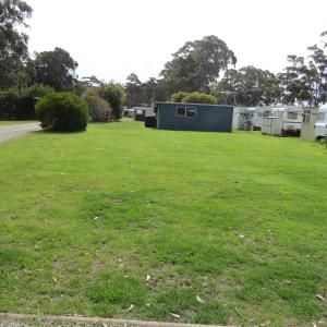 a large grassy yard with buildings in the background at Captain Cook Holiday Park in Adventure Bay