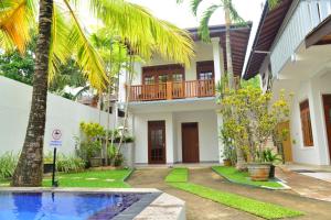 a villa with a swimming pool in front of a house at Surf Villa in Hikkaduwa