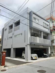 a white apartment building with a parking garage at A-Style Futenma in Ginowan